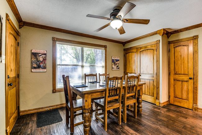 Dining room with dark wood finished floors, a textured ceiling, ornamental molding, and ceiling fan | Image 9
