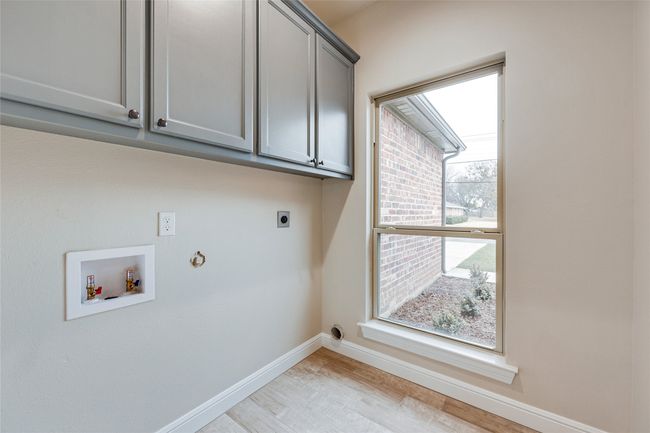 Laundry room with electric dryer hookup, washer hookup, cabinet space, baseboards, and light wood finished floors | Image 15