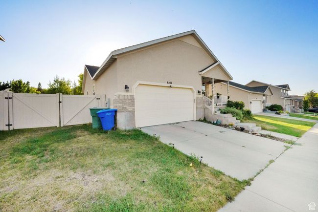 View of property exterior featuring a gate, a garage, stucco siding, a yard, and concrete driveway | Image 4