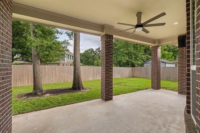 Enjoy serene outdoor living on the large, covered patio, overlooking the beautifully maintained backyard. The space is perfect for relaxing, dining, or entertaining while being surrounded by a fully sprinklered, fenced yard that ensures lush greenery year-round. | Image 24