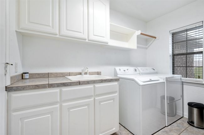 Laundry room featuring washer and clothes dryer, cabinet space, and light tile patterned floors | Image 31