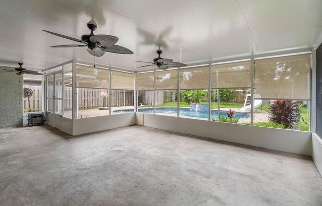 Screened in porch with sun shades and fans. View of pool | Image 17