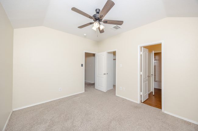 Bedroom 2 with vaulted ceiling, light carpet, a walk in closet, and a ceiling fan | Image 26