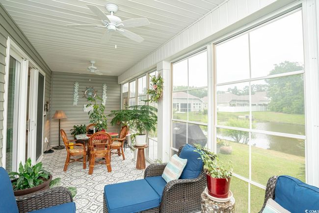 Sunroom / solarium featuring a water view, ceiling fan, and outdoor dining space | Image 34