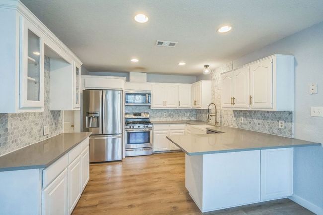 Kitchen with stainless steel appliances, a peninsula, tasteful backsplash, glass insert cabinets, and recessed lighting | Image 10