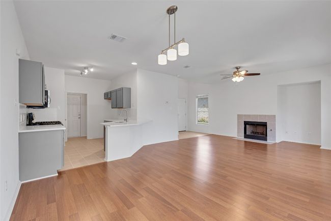 Unfurnished living room featuring a ceiling fan, light wood-style flooring, and a tiled fireplace | Image 8