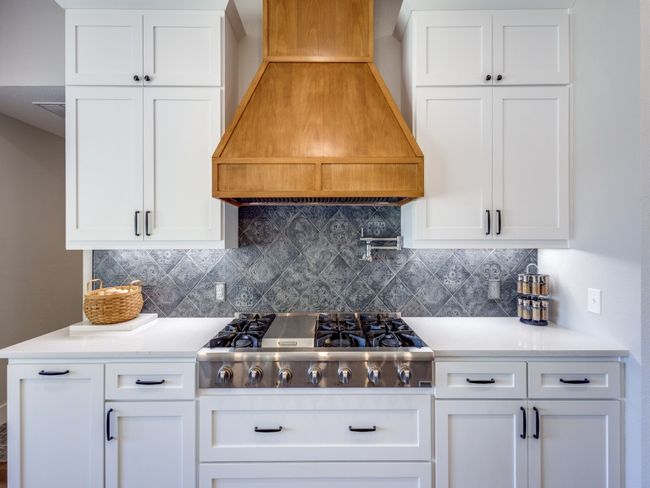Beautiful new cabinets, chic backsplash, huge built-in gas cooktop. Custom built wood vent hood. Notice the pot filler at the cooktop. Notice the undercabinet lighting. Plenty of counter space on either side of the stove provide even for convenience. | Image 11