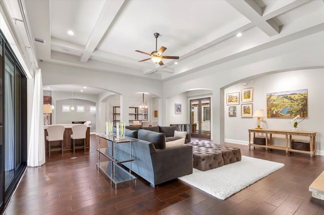 Living area featuring arched walkways, beam ceiling, a ceiling fan, and coffered ceiling | Image 7