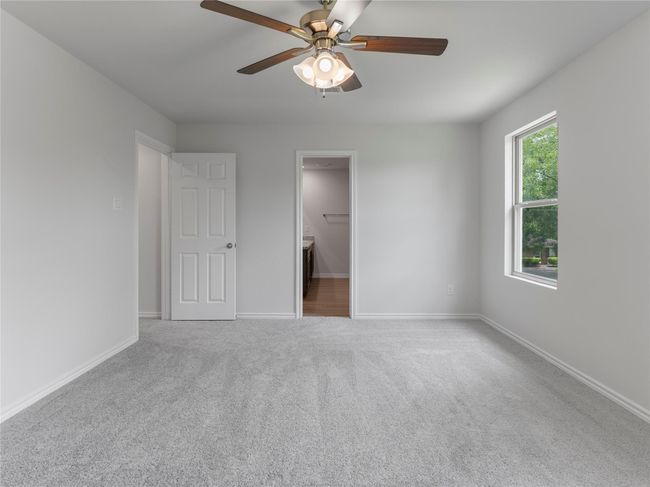 Spacious master bedroom with cozy carpet and a modern ceiling fan. | Image 17