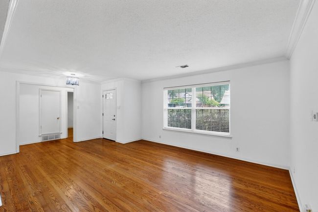 Empty room featuring a textured ceiling, wood finished floors, and ornamental molding | Image 7