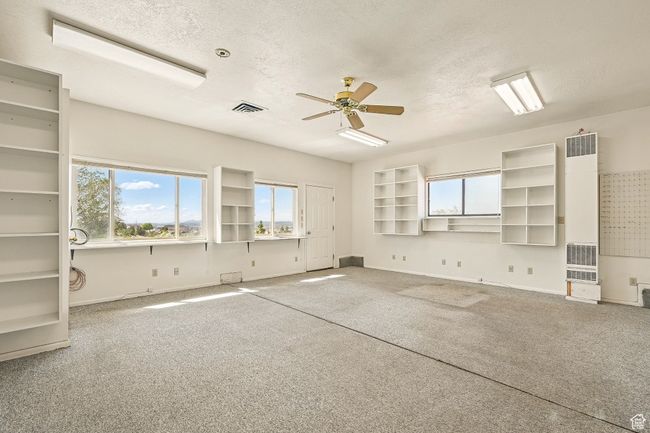 Carpeted spare room with a heating unit, a textured ceiling, and ceiling fan | Image 37