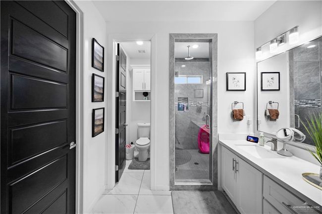 Full bath featuring a stall shower, double vanity, marble look tile flooring, and toilet | Image 22