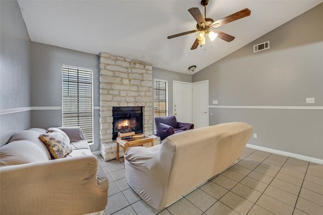 Living room with ceiling fan, vaulted ceiling, a fireplace, light tile patterned flooring, and a healthy amount of sunlight Unit B | Image 18