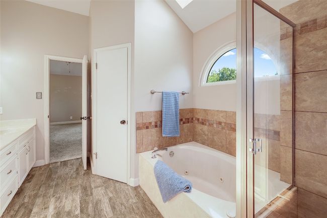 Bathroom featuring a stall shower, a jetted tub, vanity, and vaulted ceiling | Image 17