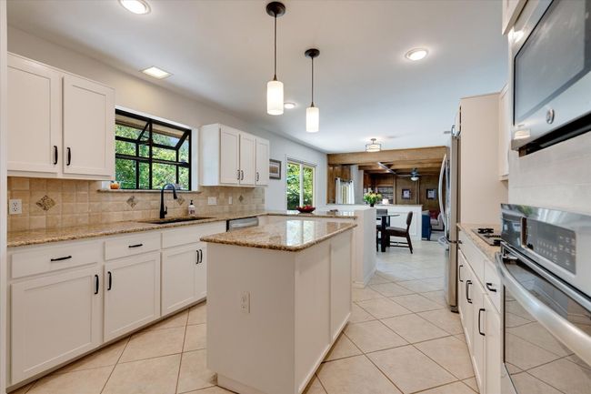 Kitchen with appliances with stainless steel finishes, a sink, a peninsula, tasteful backsplash, and a center island | Image 13