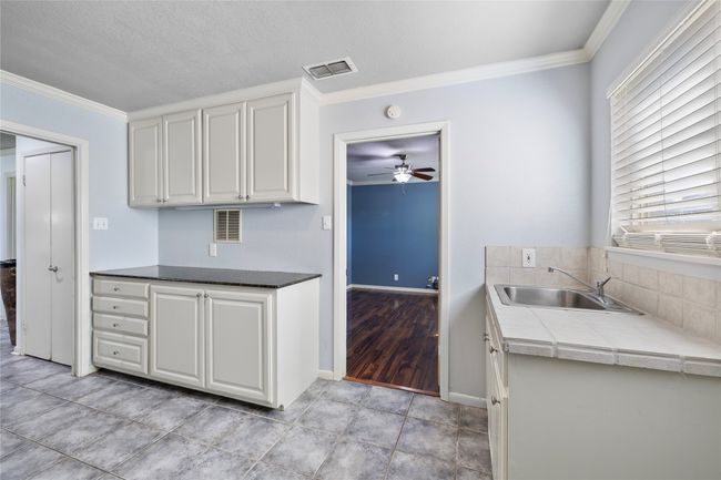 Kitchen featuring a sink, crown molding, ceiling fan, white cabinetry, and backsplash | Image 20