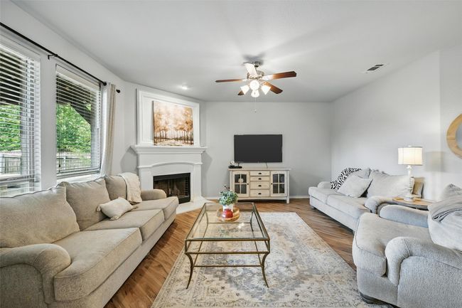Living room featuring a ceiling fan, a fireplace with raised hearth, and wood finished floors | Image 15