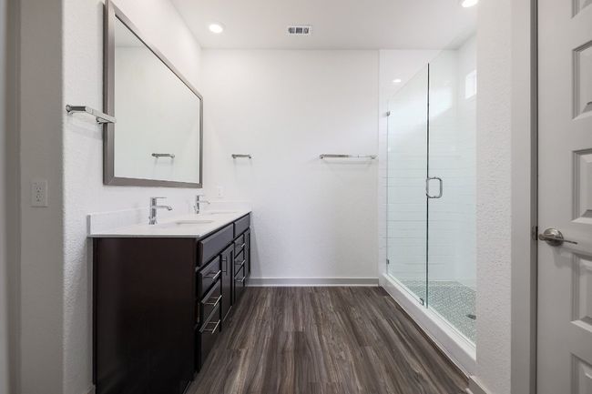 Primary bathroom with double vanity, a shower stall, wood finished floors, and recessed lighting | Image 14