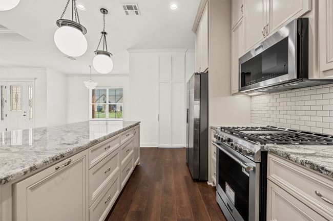 Kitchen with appliances with stainless steel finishes, decorative backsplash, dark wood-type flooring, recessed lighting, and light stone counters | Image 9
