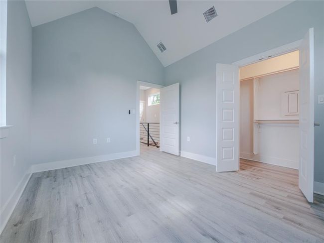 Unfurnished bedroom with high vaulted ceiling, wood finished floors, and ceiling fan | Image 15