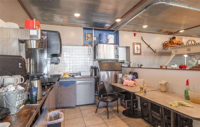 Kitchen with fridge, decorative backsplash, and light tile patterned floors | Image 13
