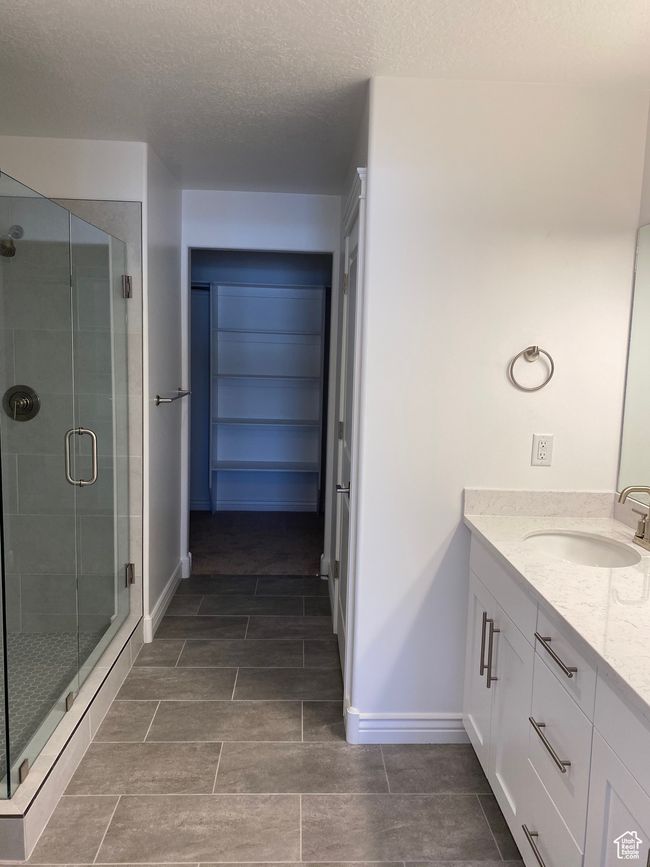 Bathroom with baseboards, vanity, a textured ceiling, and a stall shower | Image 7