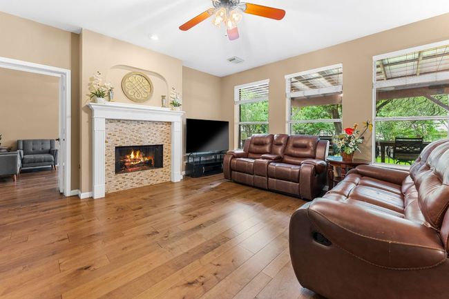 Living area with a ceiling fan, a tile fireplace, and light wood-style floors | Image 7