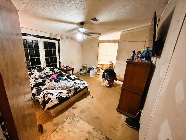 Bedroom with a textured ceiling, concrete flooring, and ceiling fan | Image 13
