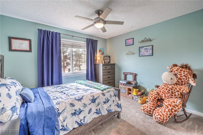 Bedroom featuring baseboards, carpet flooring, a textured ceiling, and a ceiling fan | Image 34