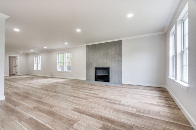 Unfurnished living room featuring crown molding, a large fireplace, recessed lighting, and light wood finished floors | Image 7