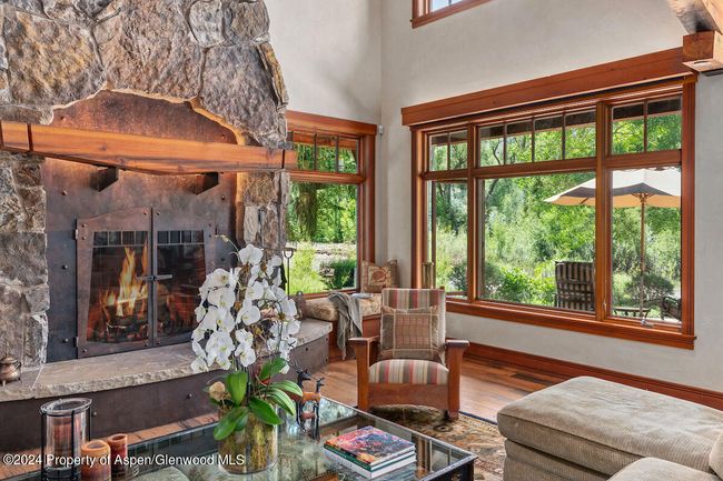 Woodburning fireplace. The entire living room is a sweep of windows overlooking the river. Electric window shades. | Image 8