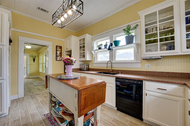 Kitchen featuring a sink, visible vents, black dishwasher, wood finish floors, and ornamental molding | Image 12