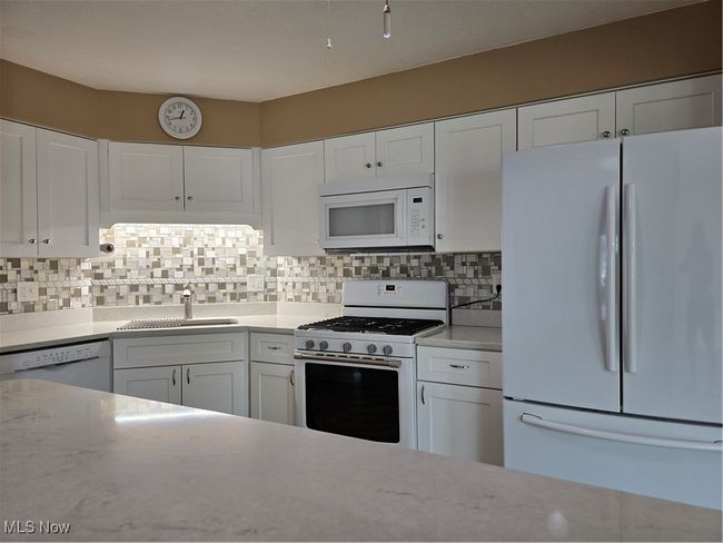 Kitchen with fridge, range, dishwasher, and white cabinetry | Image 9