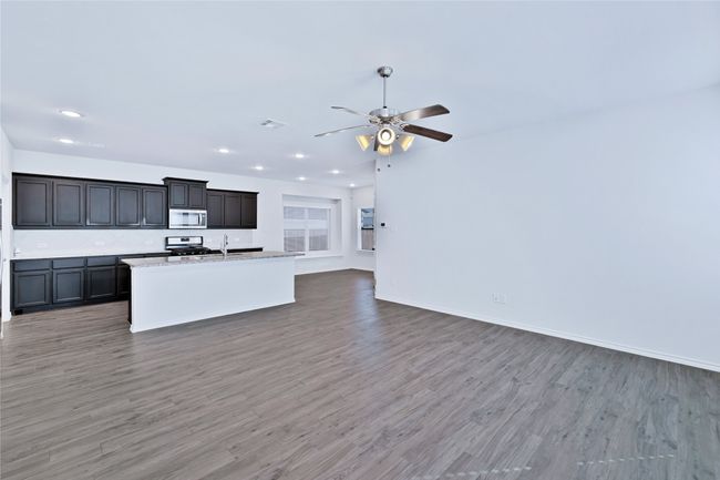 Kitchen with stainless steel microwave, open floor plan, light wood-type flooring, ceiling fan, and recessed lighting | Image 6