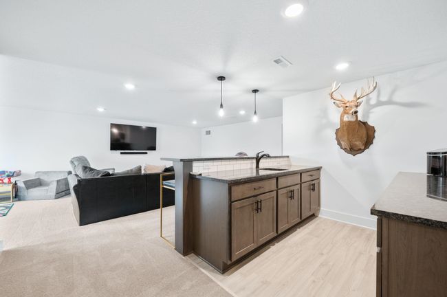Kitchen featuring a peninsula, dark stone counters, light wood-style floors, a sink, and recessed lighting | Image 23