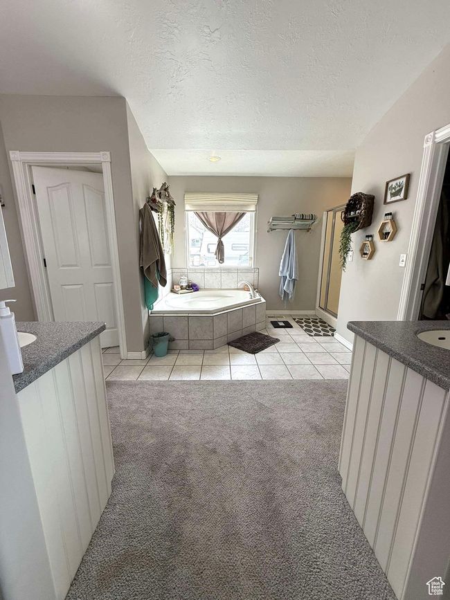 Full bathroom featuring tile patterned flooring, vanity, a textured ceiling, and a bath | Image 35
