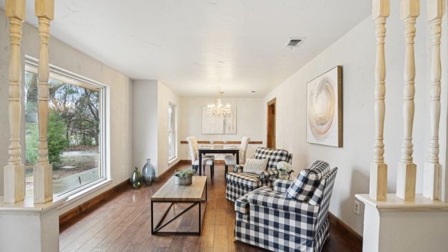 Living area featuring visible vents, a chandelier, baseboards, and wood finished floors | Image 5
