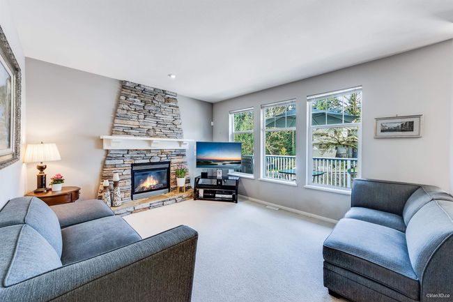Living room featuring a stone fireplace, baseboards, and carpet | Image 9