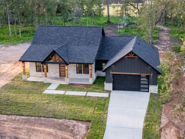 This stunning new construction blends warm Hill Country stone with sleek black board-and-batten siding and cedar accents—delivering bold modern farmhouse curb appeal with timeless charm. | Image 7