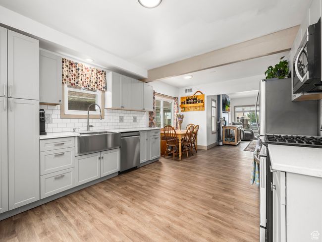 Kitchen featuring appliances with stainless steel finishes, light countertops, decorative backsplash, light wood-style floors, and recessed lighting | Image 6