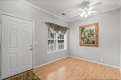 Foyer entrance with a textured ceiling, crown molding, ceiling fan, and light wood-type flooring | Image 3