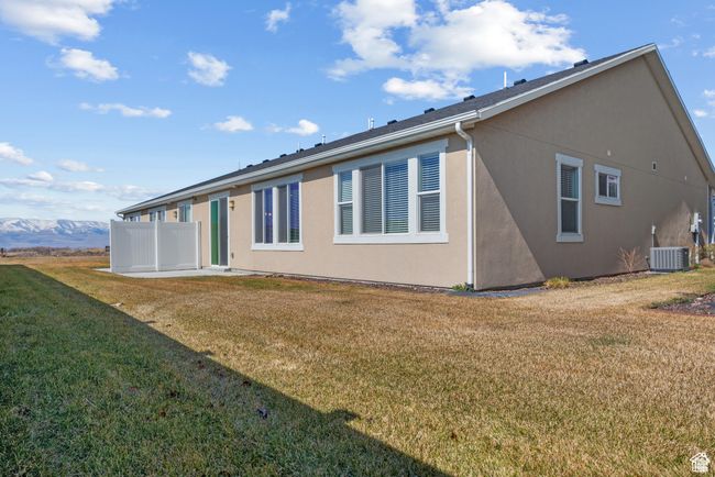 Rear view of house featuring a lawn, stucco siding, and cooling unit | Image 24