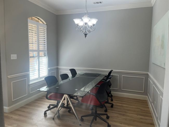 Office featuring a chandelier, wood finished floors, crown molding, a decorative wall, and wainscoting | Image 4