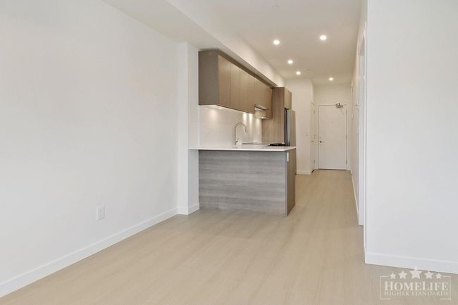 Interior space with light wood-type flooring, modern cabinets, light countertops, baseboards, and recessed lighting | Image 5
