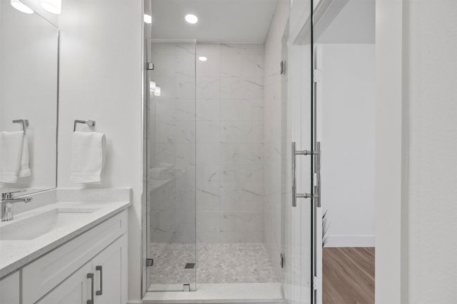 Full bathroom featuring a marble finish shower, vanity, wood finished floors, and recessed lighting | Image 13