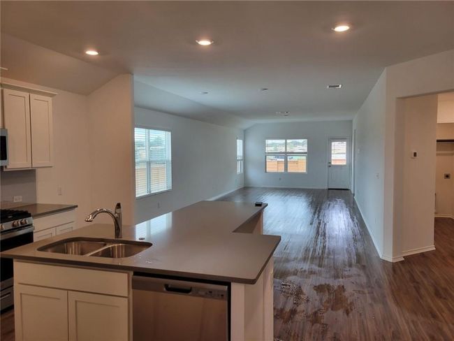 Kitchen with appliances with stainless steel finishes, open floor plan, dark wood finished floors, a kitchen island with sink, and white cabinetry | Image 10