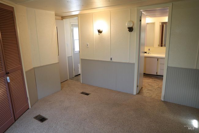 Unfurnished bedroom with light carpet, a wainscoted wall, and a closet | Image 9