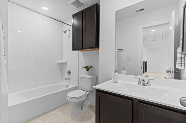 Full upstairs bathroom features a tub/shower combo, dual-sink vanity with cultured marble countertops, and stylish dark cabinetry—perfect for shared use. **Image Representative of Plan Only and May Vary as Built**. | Image 30