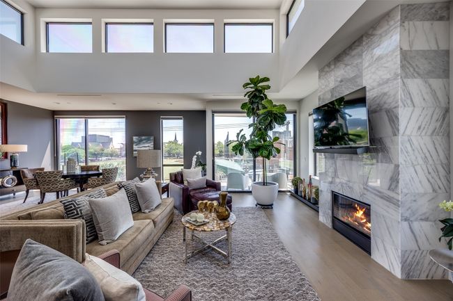 Living area featuring a fireplace, wood finished floors, a high ceiling, and a wealth of natural light | Image 6