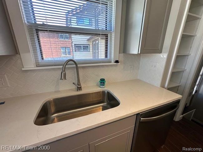 Kitchen featuring gray cabinets, stainless steel dishwasher, tasteful backsplash, light stone counters, and dark wood-style floors | Image 18